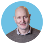 Porträttbild av Lars Tigerström, specialist i psykiatri på ADHDonline. Man med grå tröja och skjorta under. Varmt leende.